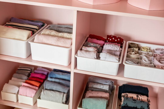 Closeup shelves pink female childish closet with neatly folded clothes Marie Kondo vertical storage