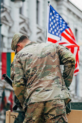 Fototapeta premium United States Marine Corps soldier on the top of a military vehicle mounting a machine gun with American and Lithuanian flag, USA or US army, NATO response force, vertical
