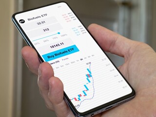 Stock world exchange market etf, stock market data on smartphone. Business analysis of a trend. Invest in international energy fund. Buying strategic biofuels ETF, biomass or ethanol funds