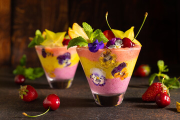 Delicious layered berry and fruit smoothie with edible flowers. Healthy dessert. Clean eating.