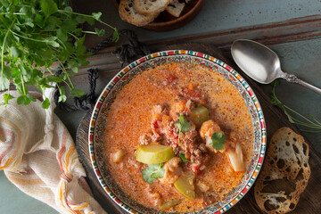plate with tomato-creamy soup with minced meat and vegetables on a wooden table