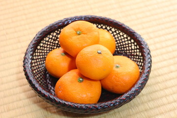 畳の上のザルに乗った愛媛のみかん。日本の冬のフルーツ。