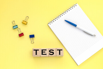 Notepad and pen on the background. Wooden cubes with word test.
