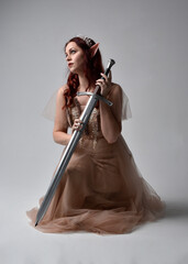  Full length portrait of pretty female model with red hair wearing glamorous fantasy tulle gown,...