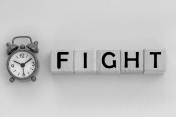  alarm clock. wooden cubes with word the fight.black and white photo