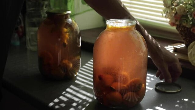 A man rolls up a jar of fruit preserves.