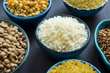 Uncooked dry cereal food group in ceramic bowls on black surface.Selected rice bowl