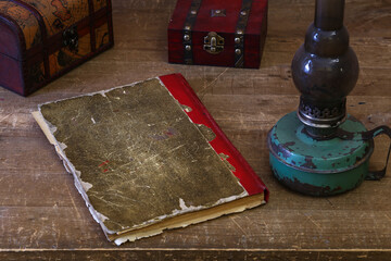 a closed old notebook for writing on an old wooden table, old strange objects, kerosene lamp
