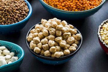 Uncooked dry cereal food group in ceramic bowls on black surface.Selected chickpea bowl