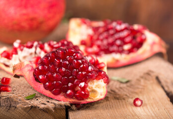Juicy pomegranate and its half Beautiful composition with juicy pomegranates, on old wooden table