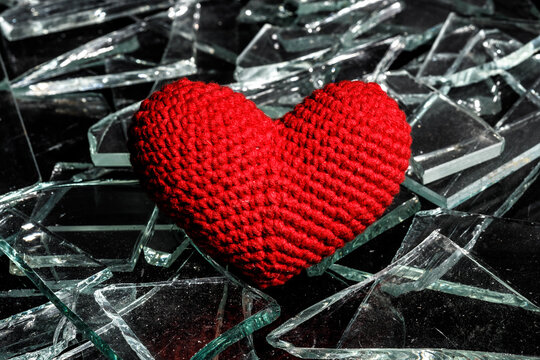 red knitted heart on broken glass. unhappy love concept