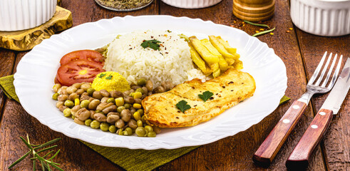 rice and beans served with french fries, grilled chicken fillet and salad, typical brazilian meal