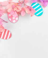 Colorful easter eggs and flowers. Border design with pink spring flowers. Happy easter greetings concept, holiday decoration background with copy space, flat lay, top view photo