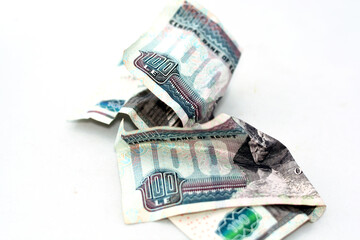 Selective focus of crumpled Egyptian money of 100 LE one hundred pounds isolated on white...