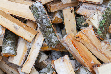 Chopped birch firewood lies in a heap on the snow in winter - 488167957