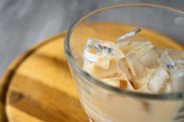 Fototapeta na wymiar Close up of glass of a iced coffee with cream milk on a wood desk. Cold brew coffee drink with ice. Copy space.