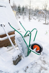 Metal garden wheelbarrow in the snow in winter - 488169319