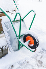 Metal garden wheelbarrow in the snow in winter - 488169334