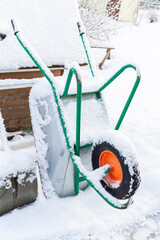 Metal garden wheelbarrow in the snow in winter - 488169337