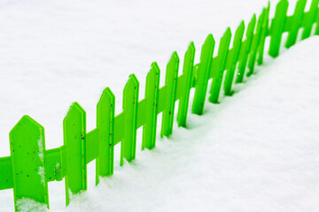 Green plastic fence in the snow in the garden in winter - 488169376