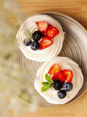 Delicious dessert of Pavlov's cake with fresh strawberries, blueberries and mint leaf. White dessert. Delicate meringue cake with berries. Cake on the table on March 8, Mother's Day, Valentine's Day.