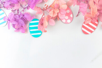Colorful easter eggs and flowers. Upper border design with pink spring flowers. Happy easter greetings concept, holiday decoration background with copy space, flat lay, top view photo