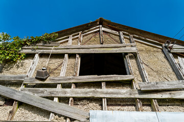 Vertical of a derelict farm building showing the poor state of repair. The roof rafters can be seen in the upper window.