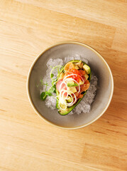 Avocado appetizer stuffed with canned salmon, red caviar, avocado slices, greens. Stuffed avocado served on ice. The concept of dietary nutrition. Gourmet restaurant appetizer. Copy space. Close up.