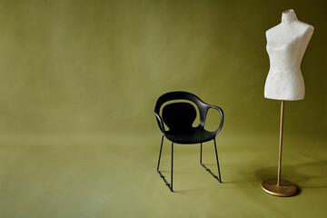 black chair and white mannequin on olive green background