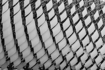 Close up view of rhombus pattern. Metallic grid pattern with white rhombus. Metal grid background. Rhombus shaped structural elements. Black and white repeating rhombus elements.