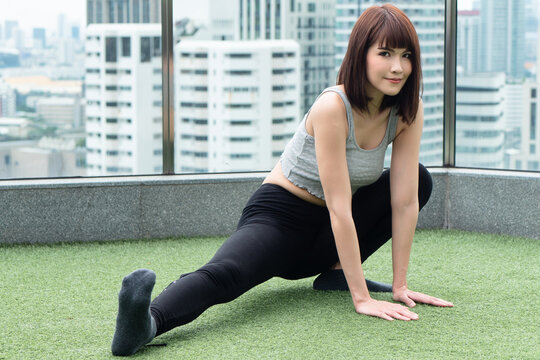 Woman practicing yoga leg stretching pose in urban environment, thigh and hip pose for hamstring muscle stretching and pelvic opening benefit