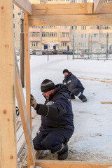 Worker in winter overalls with a hammer in his hand