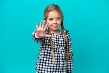 Little caucasian girl isolated on blue background saluting with hand with happy expression