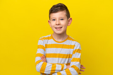 Little caucasian boy isolated on yellow background keeping the arms crossed in frontal position