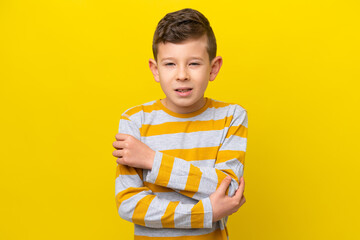 Little caucasian boy isolated on yellow background with pain in elbow