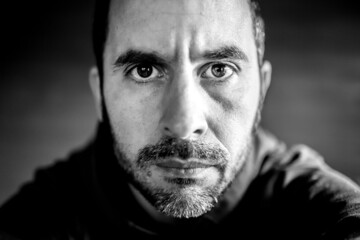 Black and white portrait of a middle aged men looking straight at the camera with a serious expression