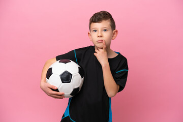 Little caucasian football player boy isolated on pink background having doubts while looking up