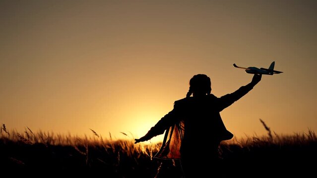 Happy girl with oy in natural park. Child runs on grass with an airplane. Chidhood dream. Happy baby girl with toy airplane at sunset. Child runs on grass in field. Dream travel concept