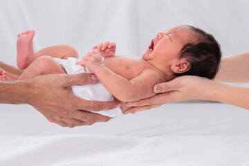 Asian little newborn baby sleep in the hands of parents protected and safe. Adorable infant sleeping in her arms mom and dad. Concept of protection of children. Toddler cring whlie parent hold.
