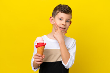 Little caucasian boy with a cornet ice cream isolated on yellow background happy and smiling