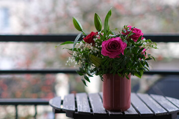 A beautiful bouquet of red and purple roses in a vase on a table outdoors