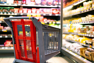 A shopping cart by a store shelf in a supermarket