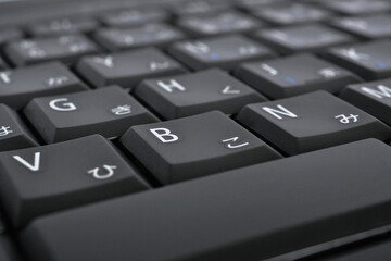 Japanese typing. Black laptop keyboard. Symbols on the buttons of hiragana. Electronic commerce in Japan. IT technologies and data storage. Dark computer background or wallpaper