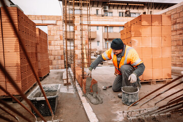 Professional worker using pan knife for building brick walls with cement and mortar