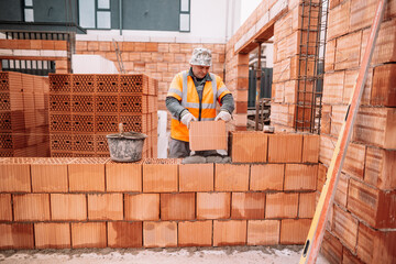 industrial worker, bricklayer, mason working with bricks and building house