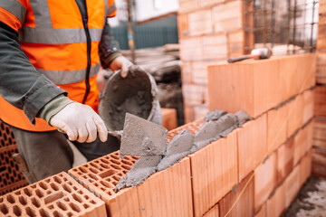 Professional construction worker using pan knife for building brick walls with cement and mortar