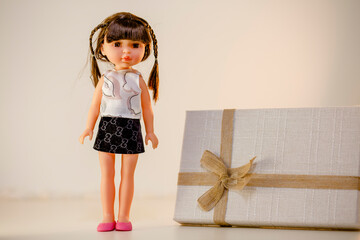 Creative and fashionable photoshoot of adorable doll standing next to the gift