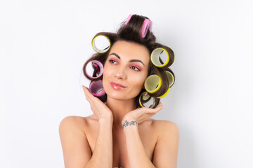 Beautiful housewife. Young cheerful woman with hair curlers and bare shoulders getting ready for a...
