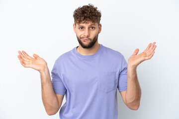 Fototapeta premium Young handsome caucasian man isolated on white background having doubts while raising hands