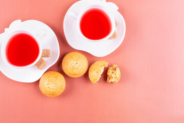 Homemade rice muffins with raisins and two cups of raspberry tea on a pink background. Space for text. Rice flour cupcakes. The concept of proper nutrition, gluten-free diet, baking for diabetes.